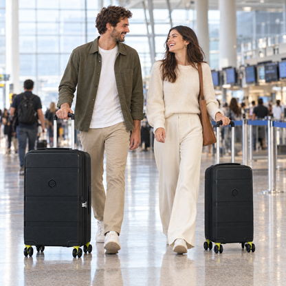 Set de 2 maletas BG Berlin ZIP² negras (grande y cabina) llevadas por una pareja en el aeropuerto